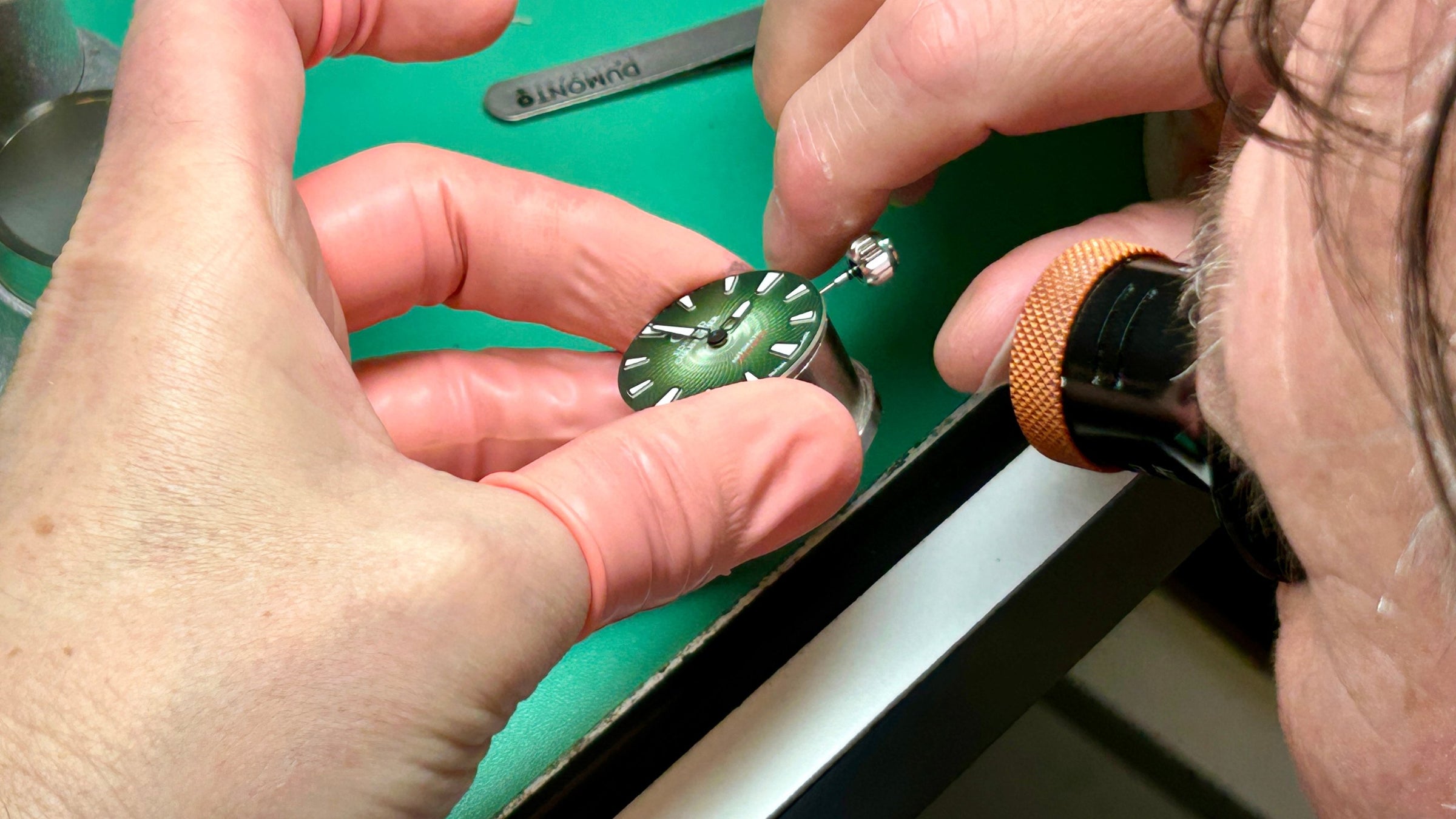 A Forest Green colour watch dial from an Edward Christopher Manta luxury watch, dive watch & sports watch from Edward Christopher watch shop being assembled by a watchmaker
