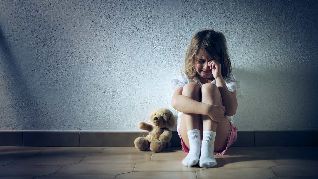 Young girl crying sitting on floor wit teddy bear