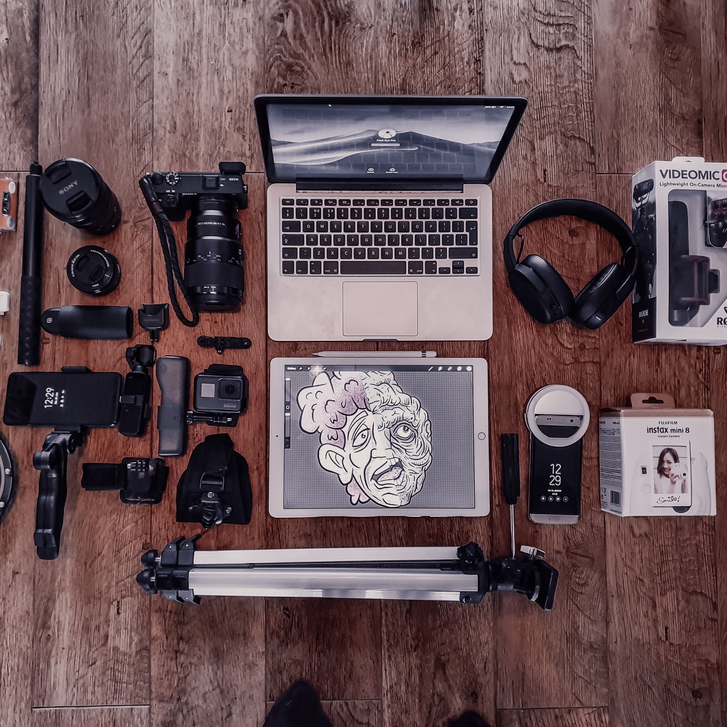 Apple MacBook laptop computer and Apple iPad on wood floor surrounded by camera equipment