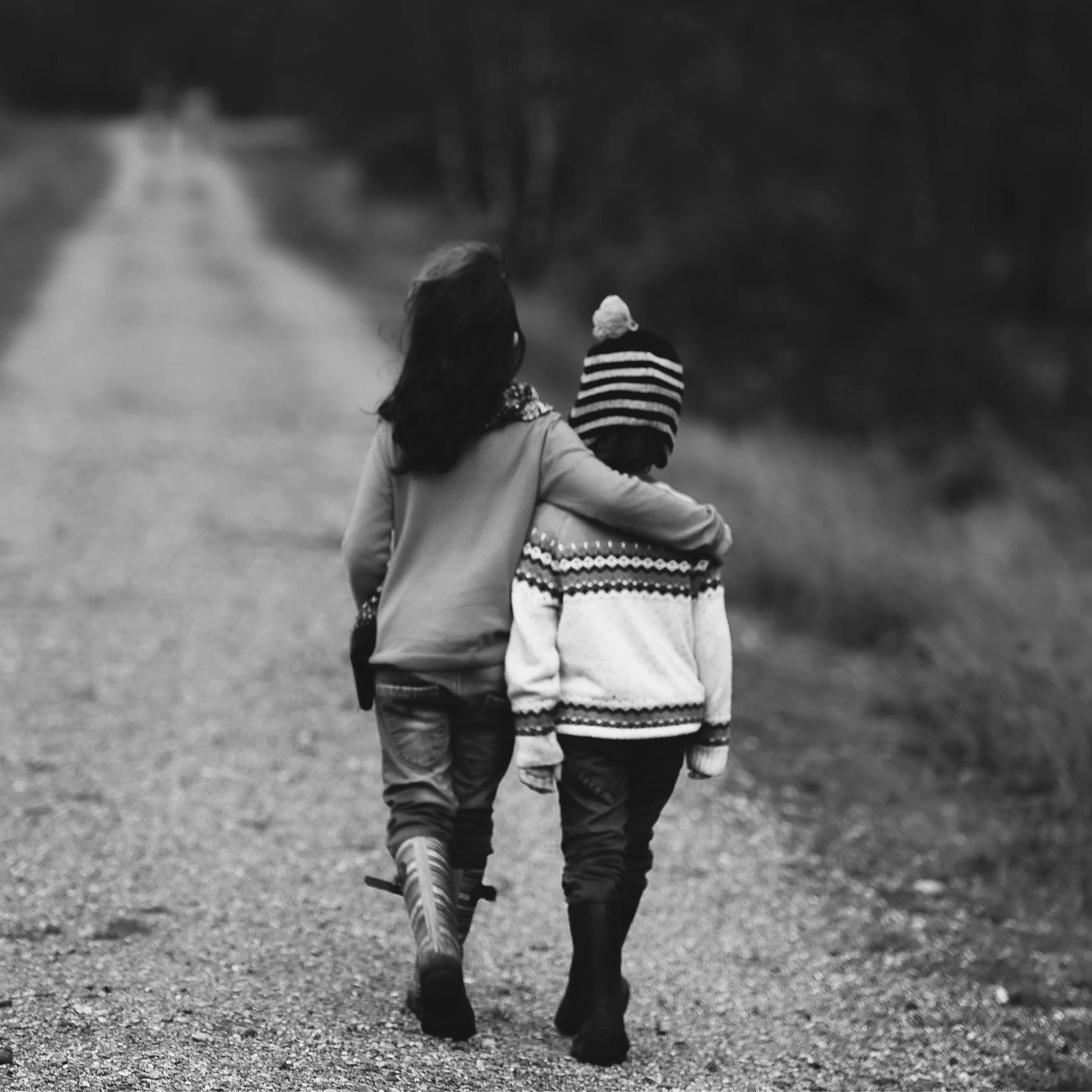 Two children hugging each other walking along a gravel path signifying the Edward Christopher luxury watch brand's mission to support children & young people