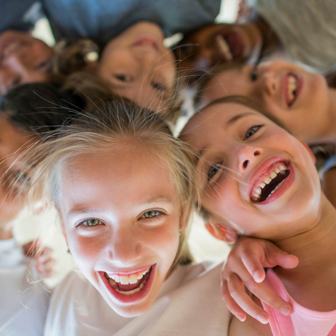 Group of laughing children together looking down at the camera showing their humour 